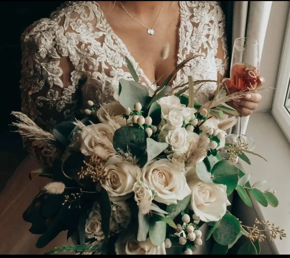 Bride holding a flower bouquet designed by No8 Studio Florist and a glass of champagne